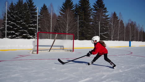 young girl practicing ice hockey on an outdoor rink