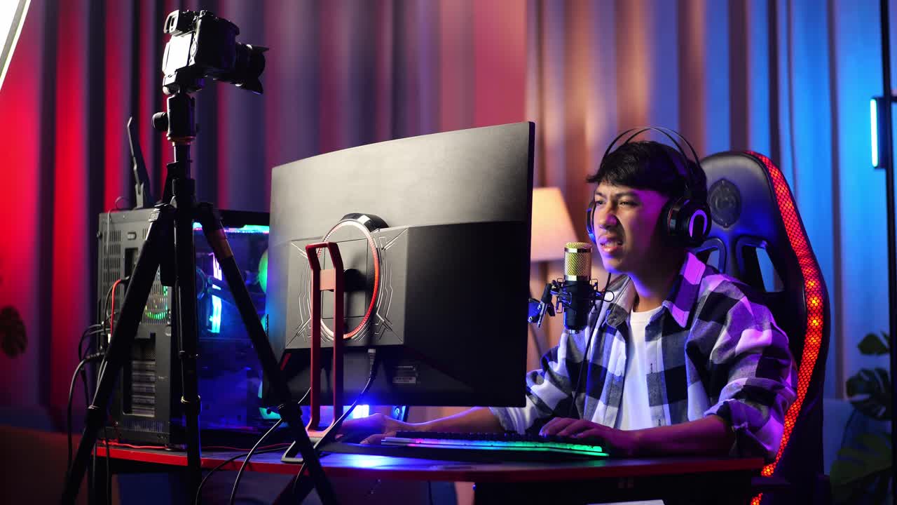 아시안 소년 스트리머는 개인 컴퓨터에서 네트워크를 통해 게임을하는 동안 스트레칭합니다. 라이브 스트리밍 비디오 게임, rgb led 스트립 라이트에 의해 조명 된 책상