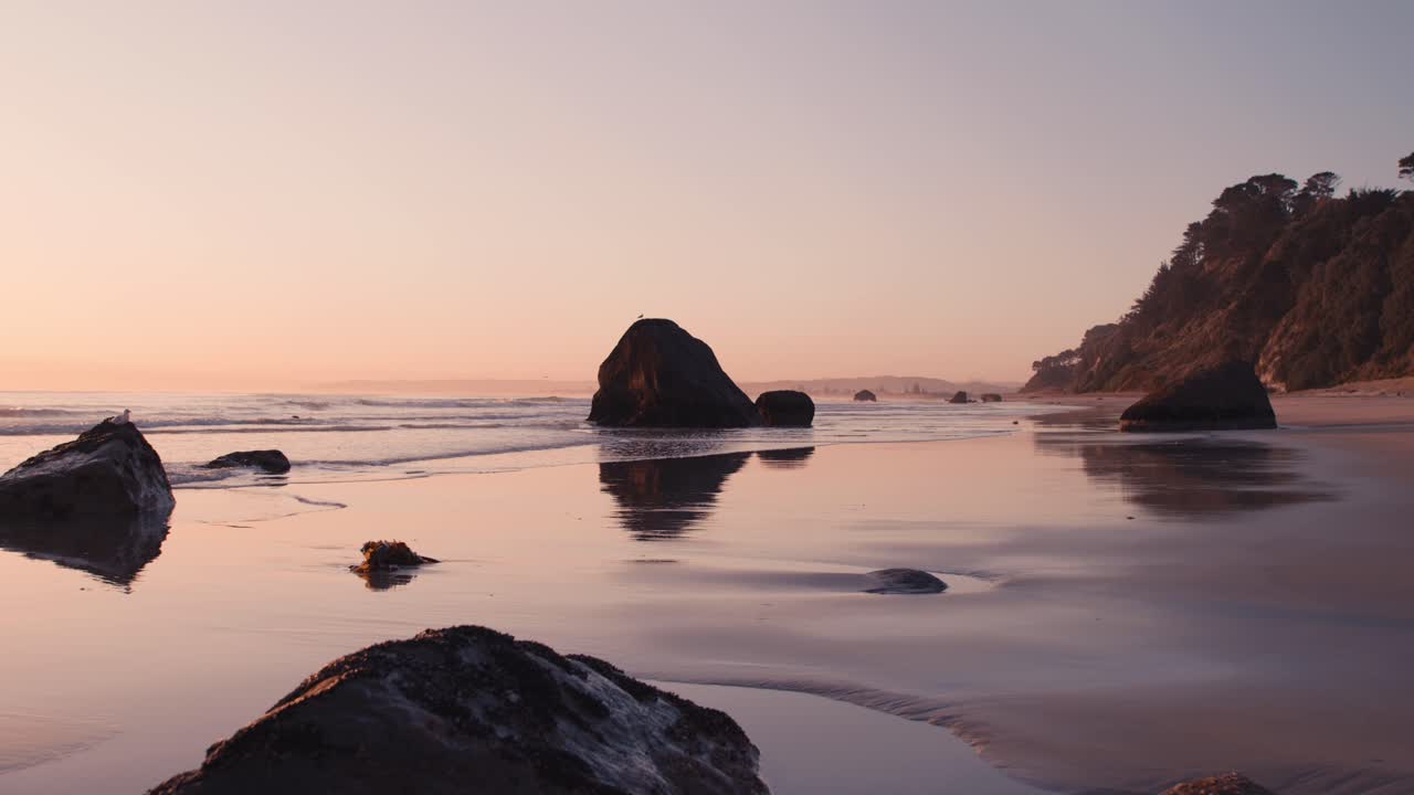 rocas esparcidas en una playa suave y luminosa durante el amanecer de ensueño