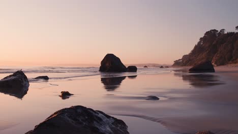 rocks scattered on smooth luminous beach during dreamy morning sunrise