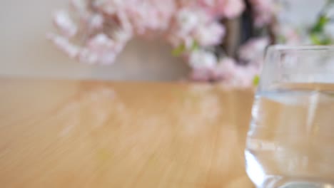 water glass on wooden table with pink flowers