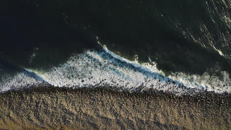 static aerial above ocean waves rhythmically breaking on rocky oregon shore