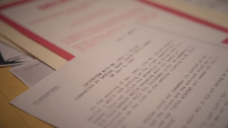 close up on hand using red rubber stamp to mark document report as classified. government agency person or analyst labels paper with official classification. top secret sensitive military information