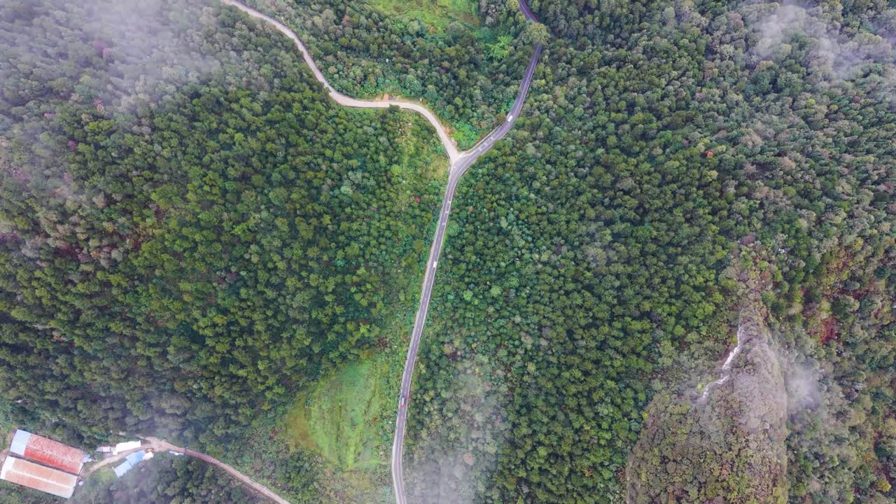 Aerial view of the lush hills and winding roads in the Guizhou Province, China. Showcasing scenic mountain terrain surrounded by dense forest, perfect for nature and travel content