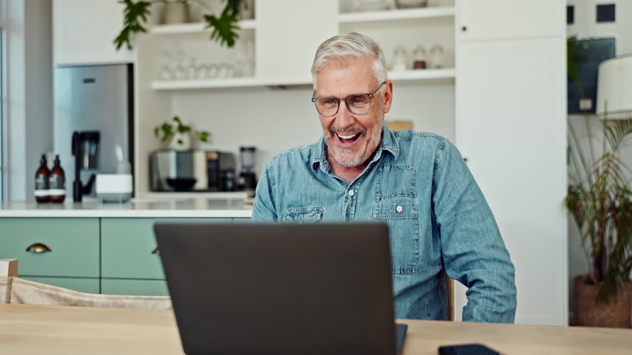 hombre mayor trabajando en una computadora portátil en casa