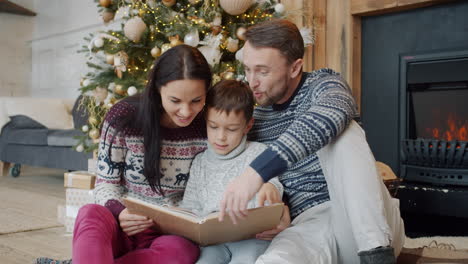 family reading a photo album by the fireplace during christmas