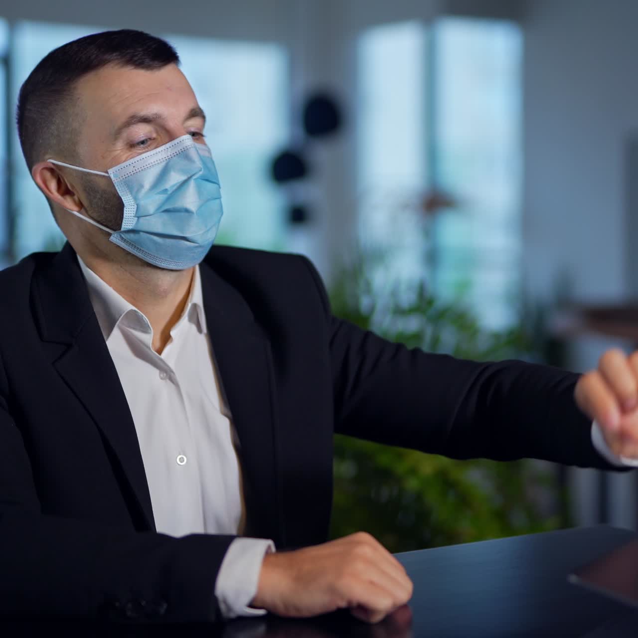 Man in suit putting on mask while sitting at the table. Businessman opens and clothes laptop, tries to open it again and fails. Close up