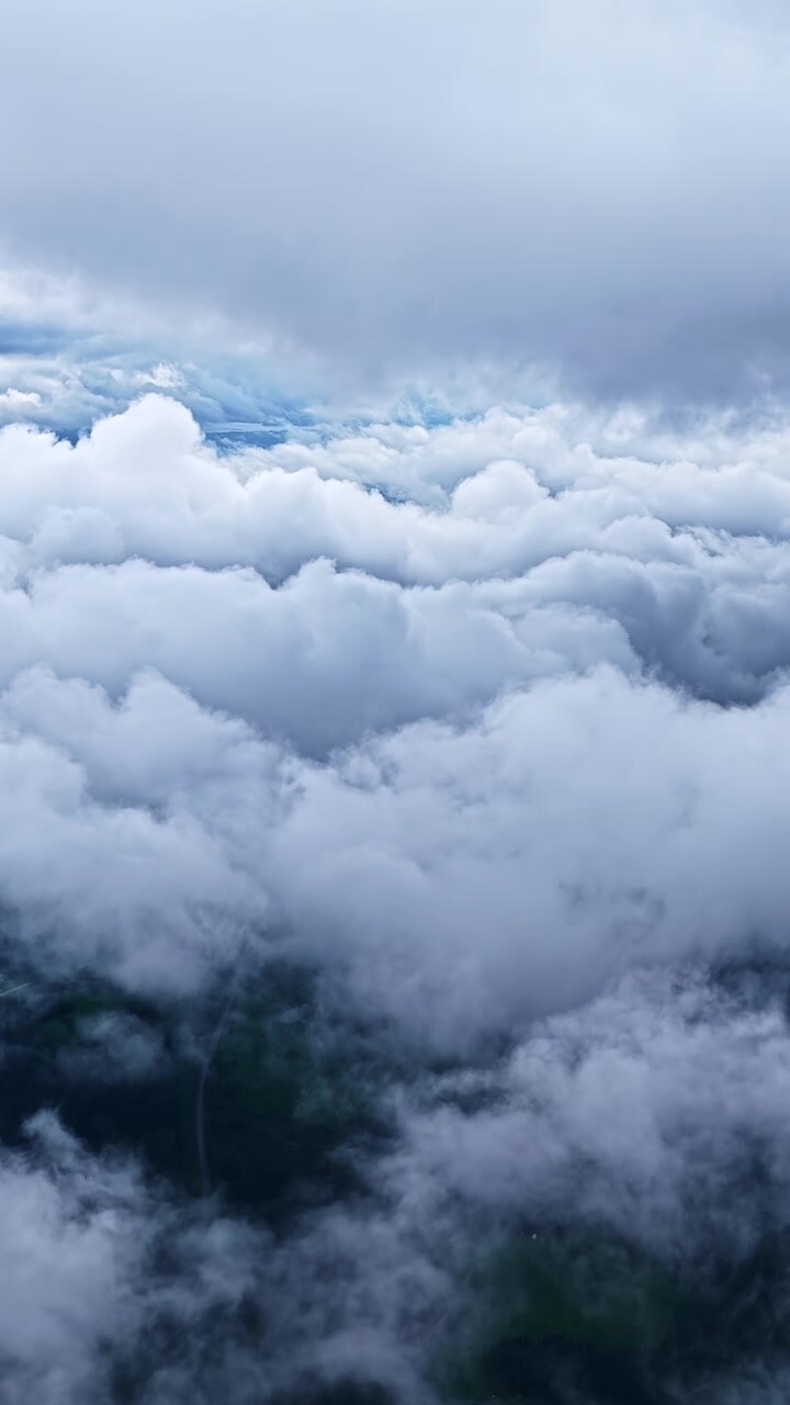 Breathtaking aerial perspective flying over a blanket of white, fluffy clouds and mountains
