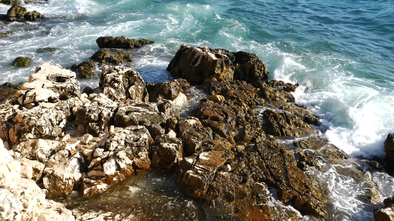 primer plano de las piedras en la playa albanesa siendo destrozadas por las olas del mar jónico