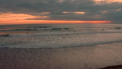 4K UHD aerial shot of a wide sandy Pacific beach in Costa Rica at sunset with a beautiful colored sky and vibrant clouds above the ocean.