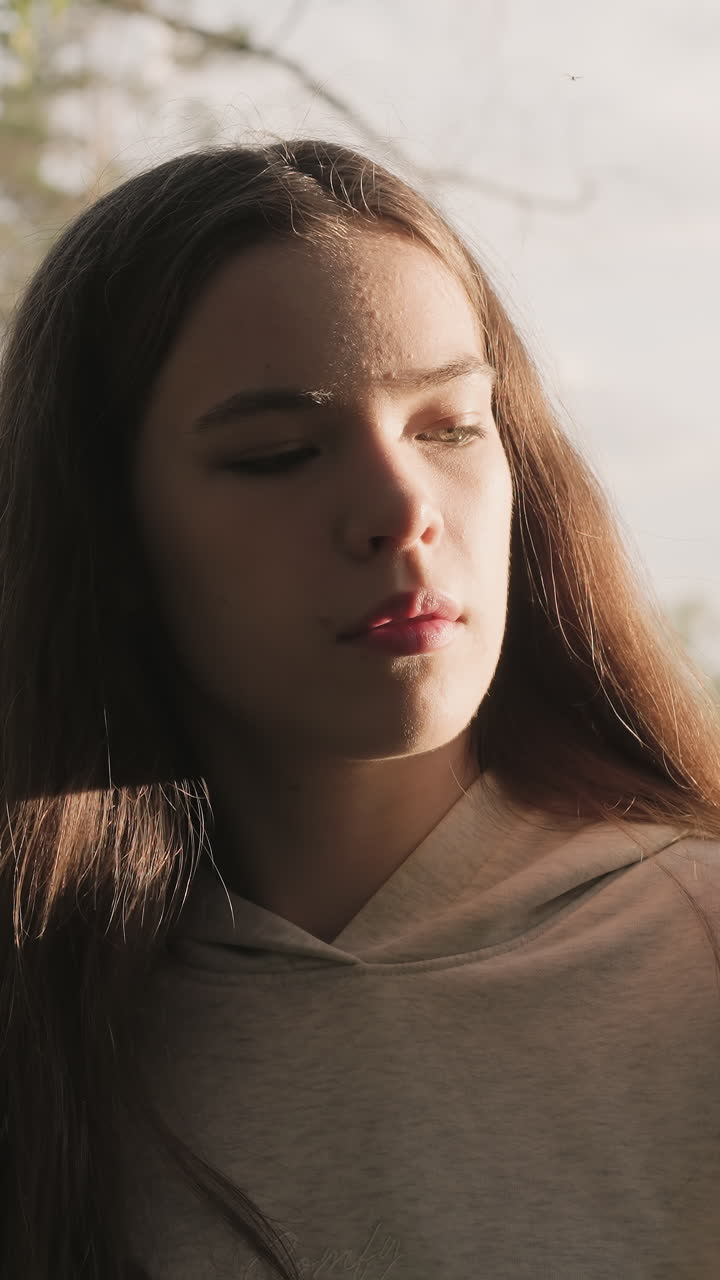 una mujer triste está cerca de un árbol iluminado por la luz del sol. una joven con el pelo largo y suelto piensa en la relación pasada en el bosque. un pasatiempo en la naturaleza para aliviar el estrés