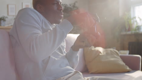 young black man playing console game at home