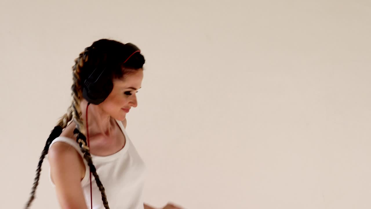 피그테일을 입은 여자가 헤드폰과 춤으로 음악을 듣고 있습니다.