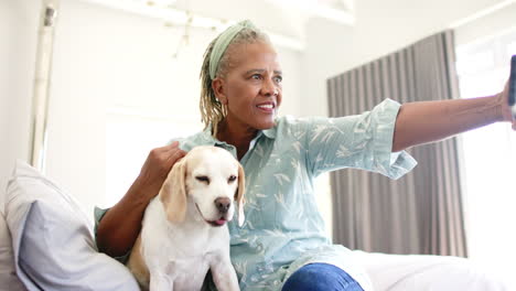 african american senior woman taking selfie with dog at home