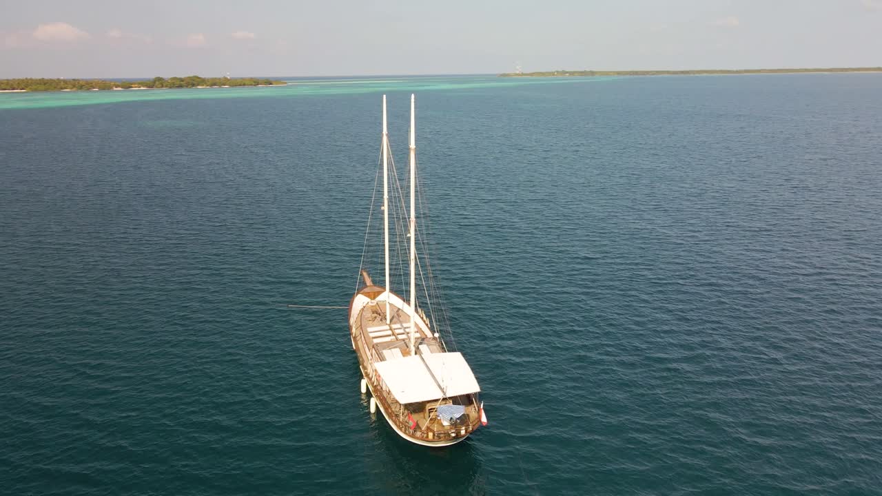 푸른 나무가 있는 몰디브 섬 옆 푸른 바다를 항해하는 요트 위에서 갈퀴