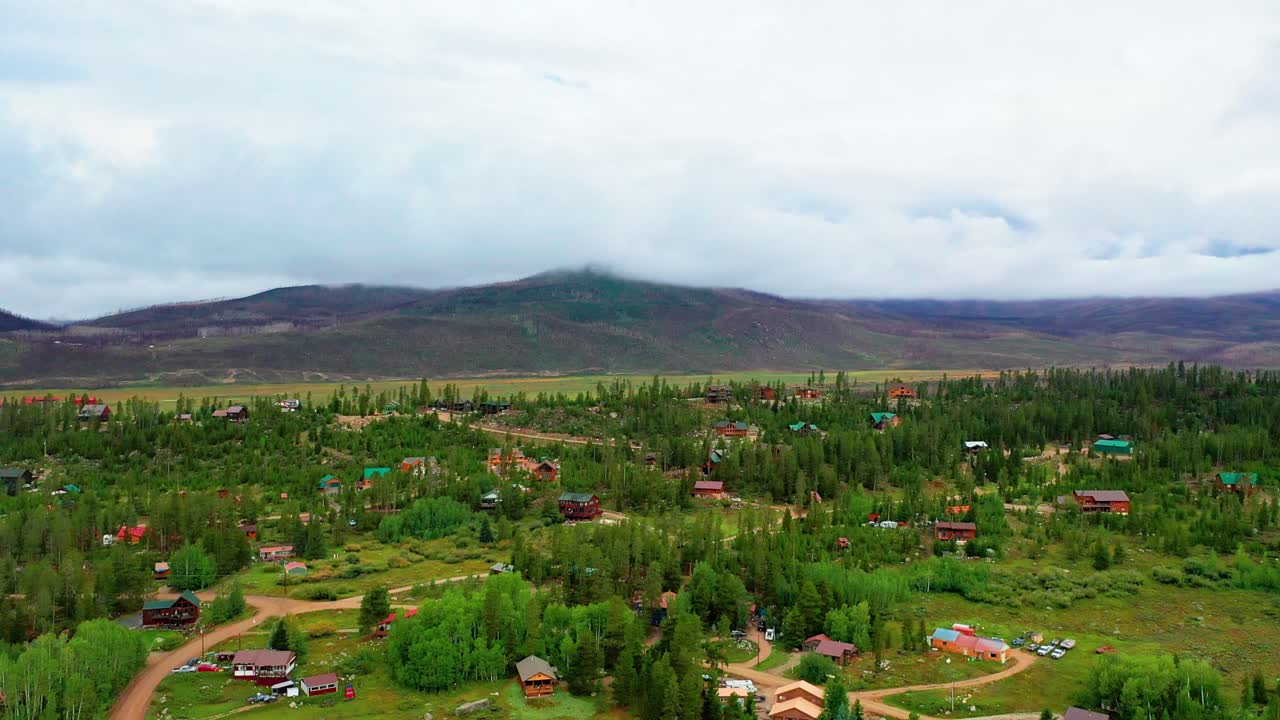 vista aérea de un pueblo de montaña en verano rodeado de bosque de pinos y colinas en las montañas rocosas en un día nublado