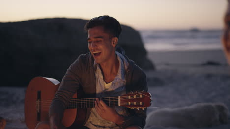 Beach-bonfire-with-group-of-friends,-drinking-beer-and-playing-guitar