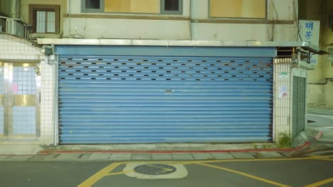 blue garage grate covering shop entrance in asia at night, push in