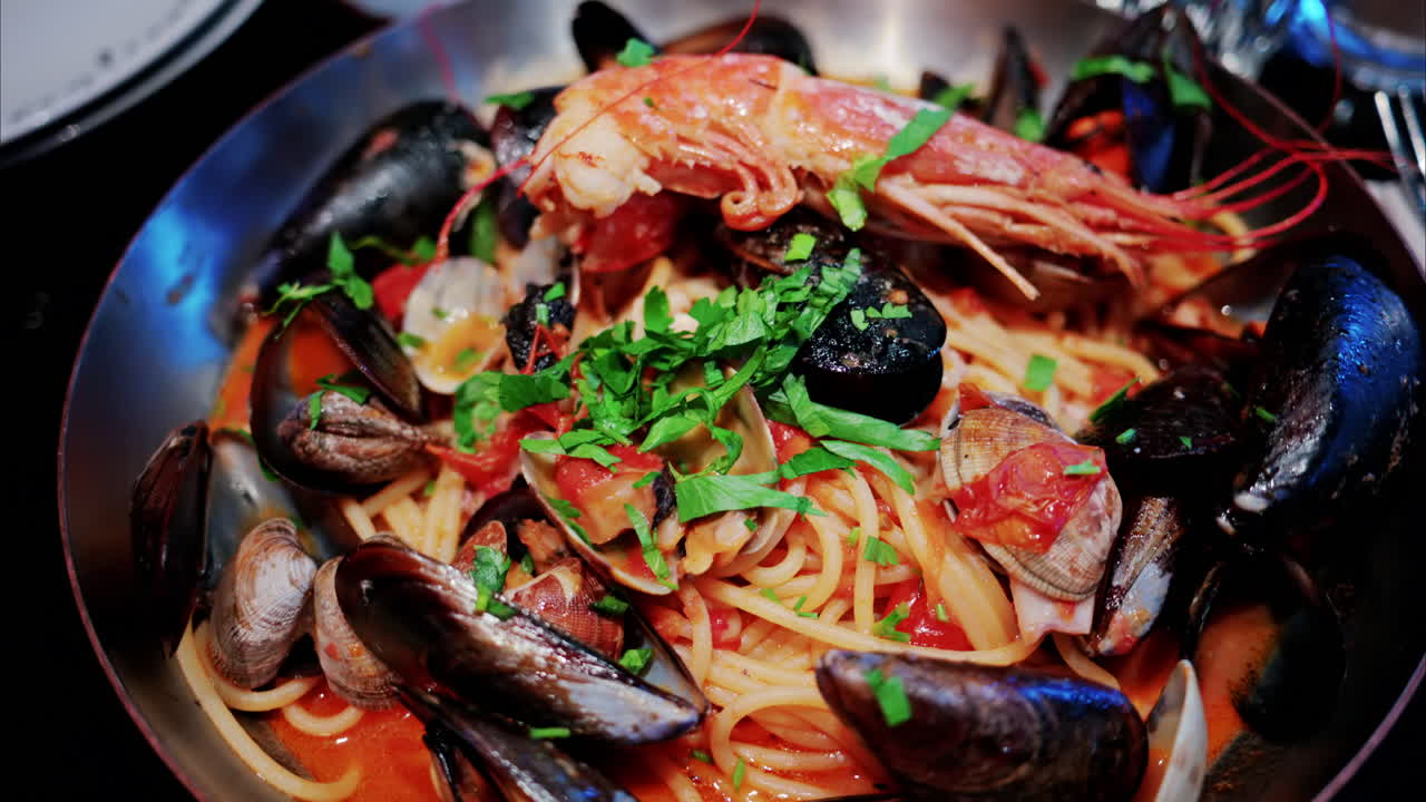 Close up of pasta with tomato sauce and mussels in a pan