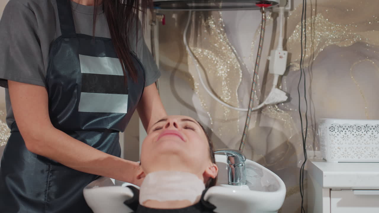 Esperienza di lussuoso massaggio al cuoio capelluto: cliente sottoposto a un delicato massaggio in un ambiente tranquillo da salone, sessione di cura dei capelli all’insegna della coccola con applicazione di prodotti di lusso e ambiente rilassante