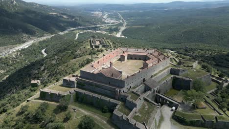 drone view of bellegarde fort on sunny day at le perthus, france surrounded in greenery during daytime.