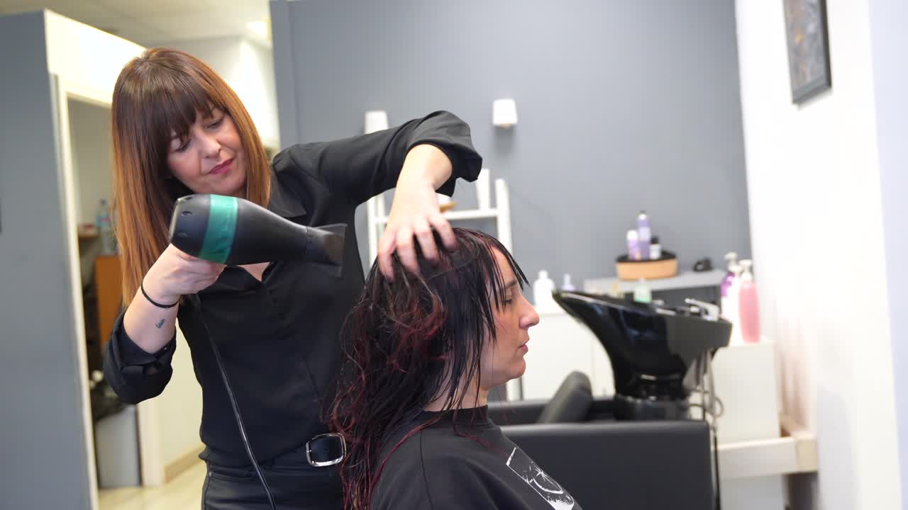 Hairdresser drying customer's hair in salon