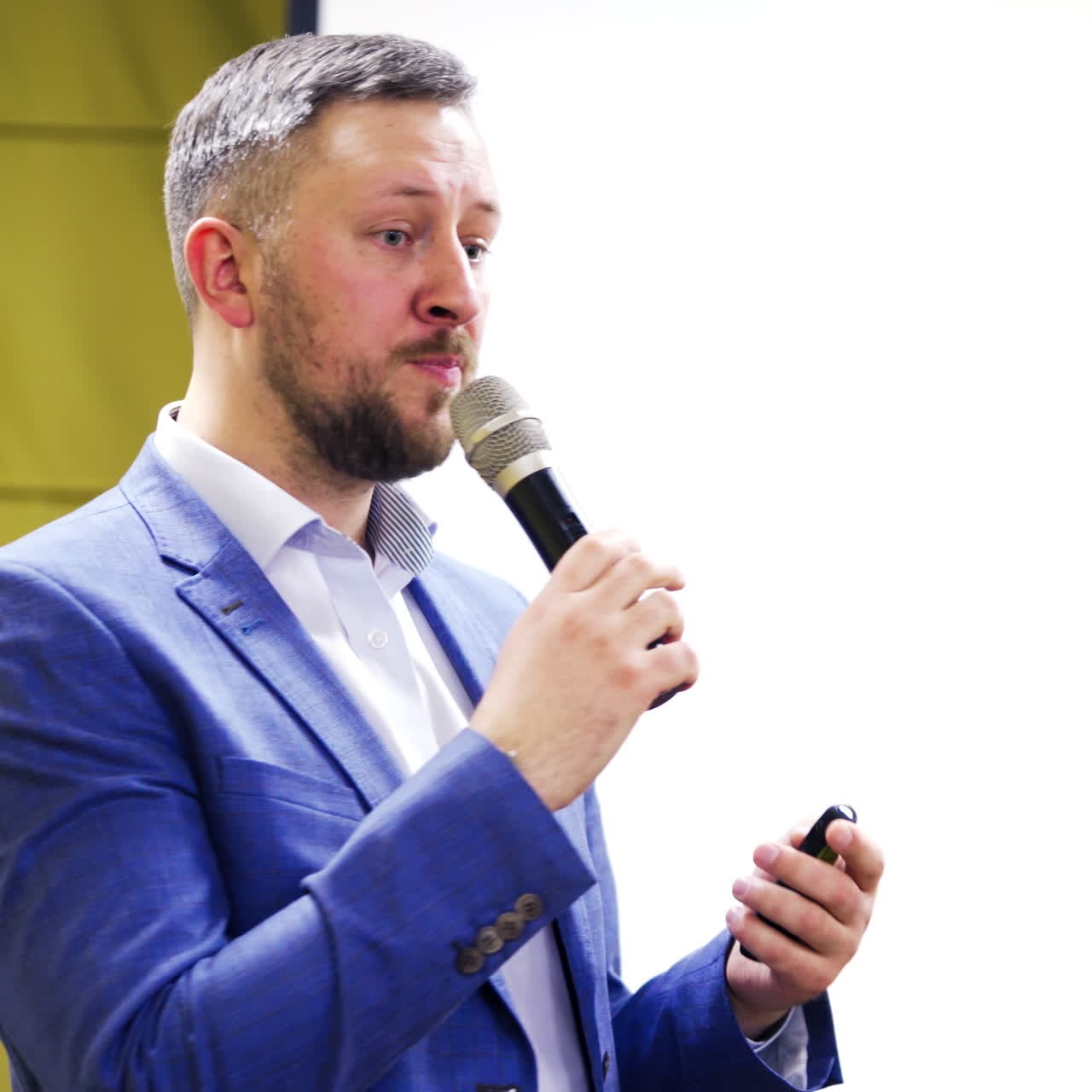 Handsome businessman speaking and showing some information on the screen at business forum. Executive leader talking into the microphone indoors. Close-up