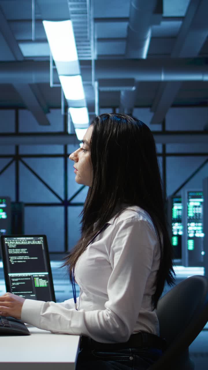 Programmatrice al lavoro su un portatile in un data center