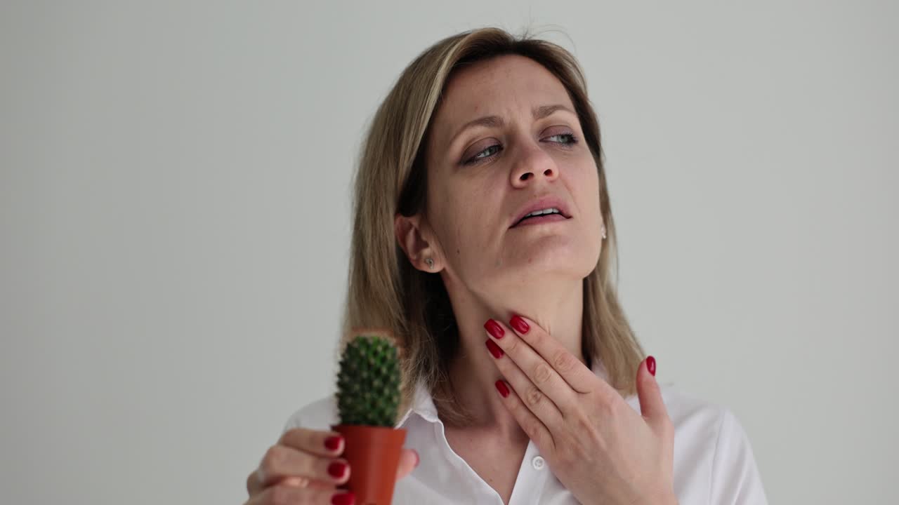 Donna con mal di gola mentre tiene in mano un piccolo cactus