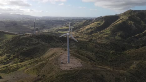 drone flying to windmill tower, rotating turbine generating renewable energy in new zealand