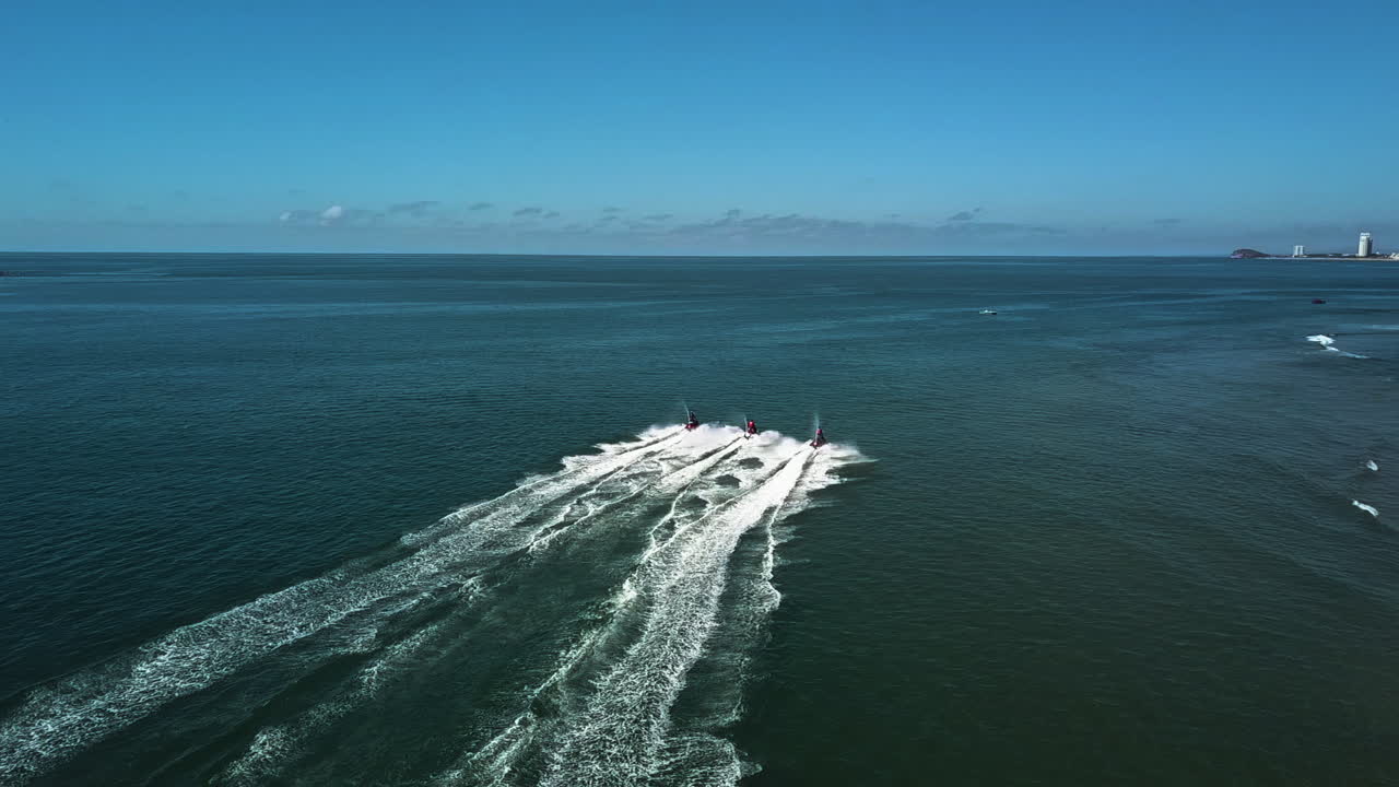 Three People Riding Jetskis on the Ocean