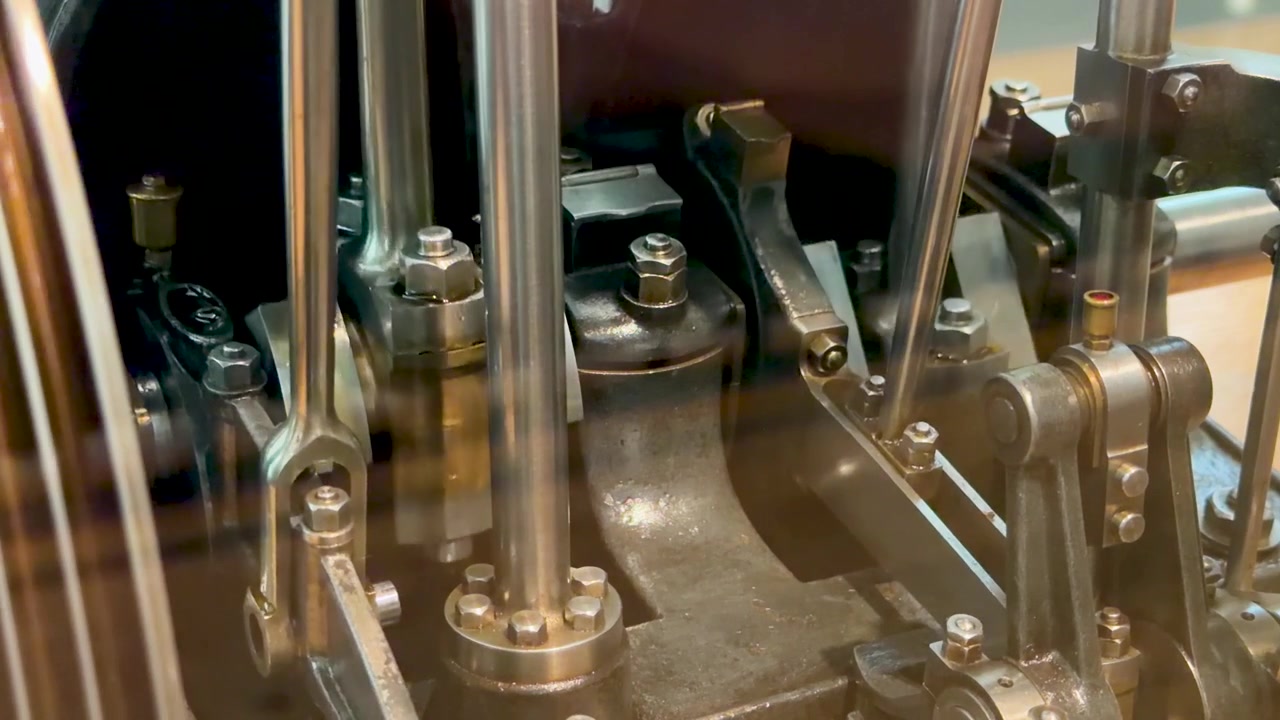Close-up shot of a polished metal industrial engine model operating with rhythmic mechanical movement.