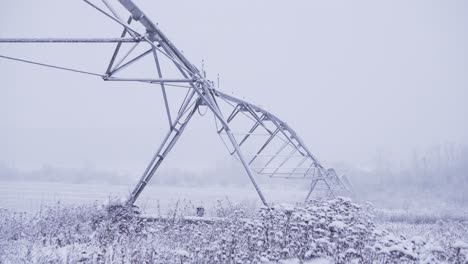 toma de 4k de equipo de riego de pivote central en un campo agrícola abierto, durante una tormenta de nieve