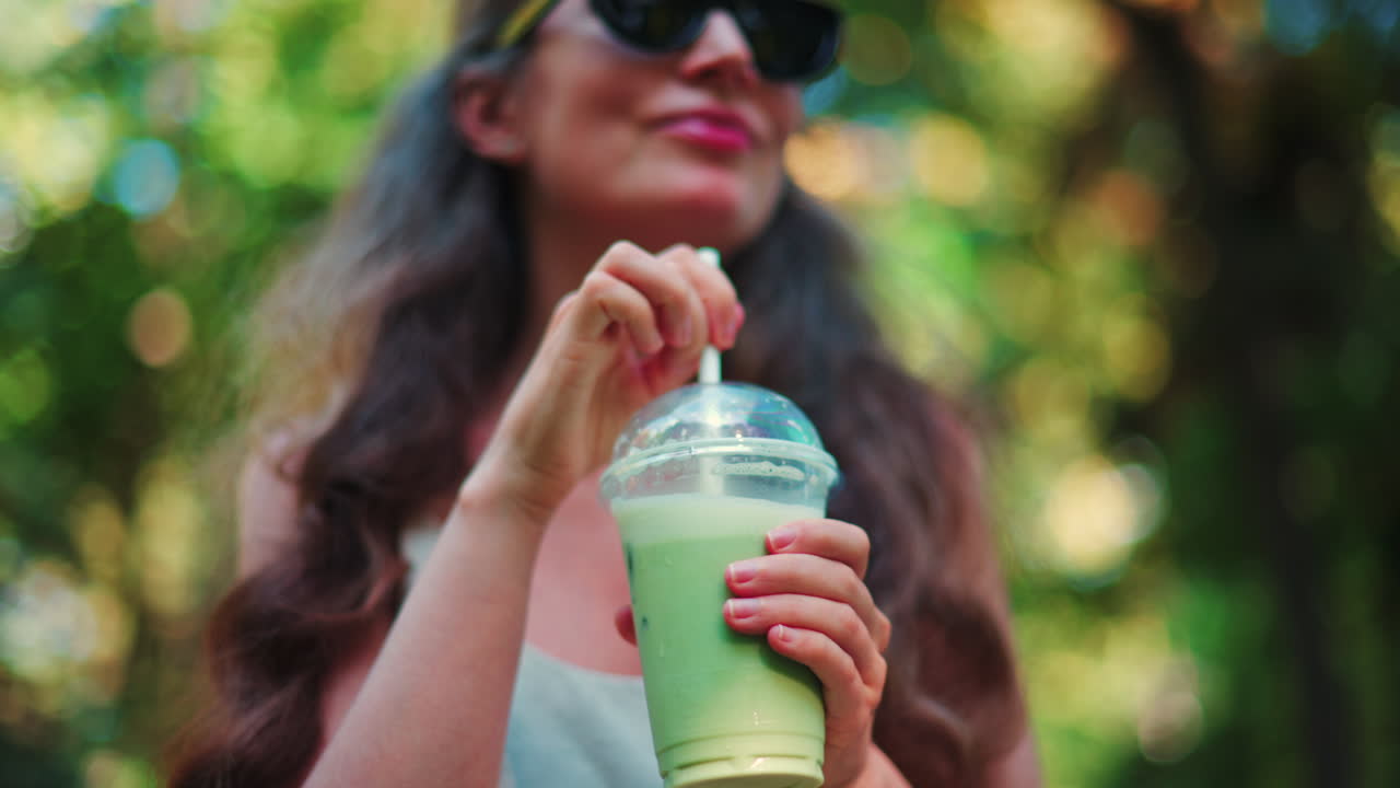 Close up of woman's hand holding an iced matcha latte outdoors