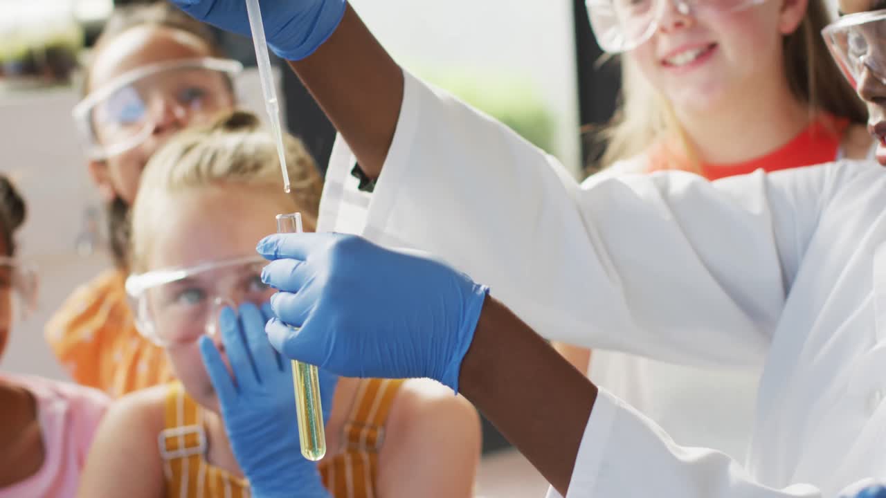 Diverse female teacher and happy schoolchildren having science class in school lab