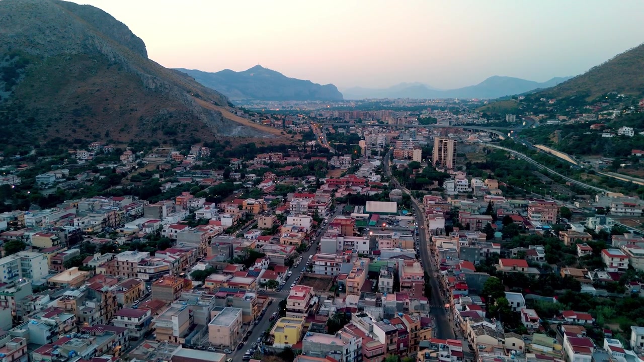 Vista aérea al amanecer sobre los densos tejados arquitectónicos y las estrechas calles costeras del pueblo histórico de Sferracavallo, Palermo, Sicilia, Italia, iluminado por la luz de la mañana.