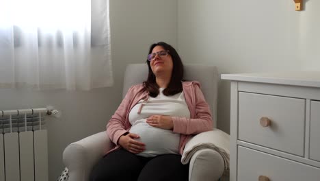 young pregnant woman crying excited about her future baby on a rocking chair at home