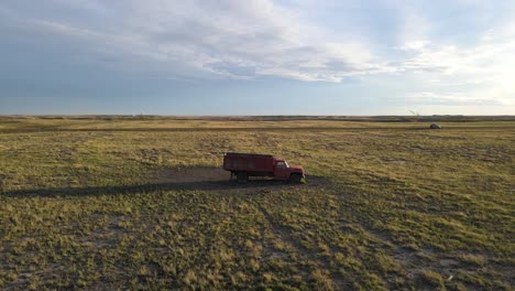 Aerial-drone-clip-of-a-red-isolated-truck-parked-in-the-middle-of-a-dry-plain-in-a-countryside-landscape