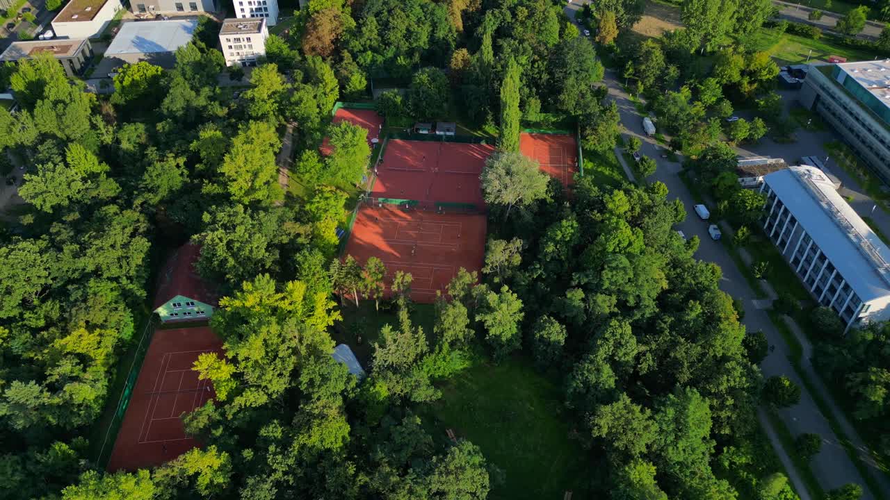 several tennis courts nestled within a dense forest, providing a tranquil escape in the heart of the city Berlin. Stunning aerial view flight drone camera pointing down