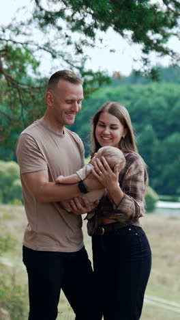 first time parents spend time with their newborn baby in the nature out of city. smiling couple talk to their child. vertical video
