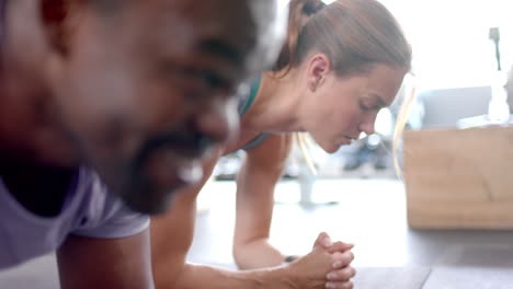 Fit-African-American-man-and-young-Caucasian-woman-exercising-together-at-home