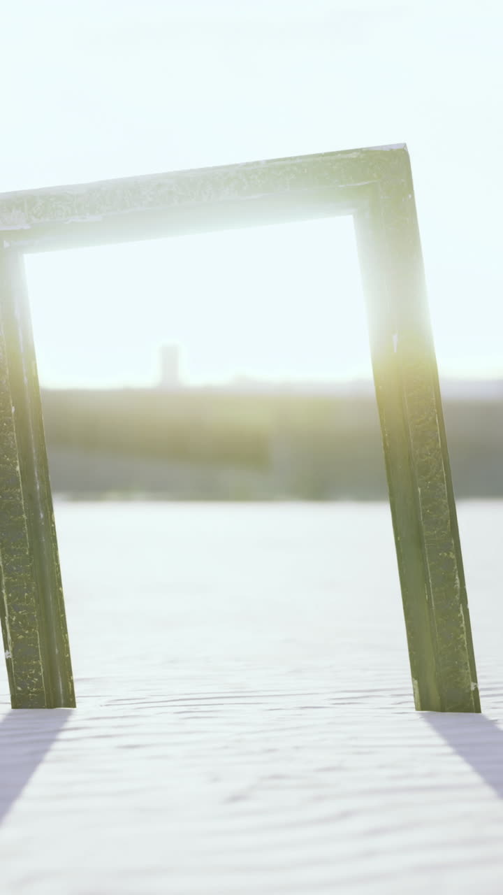 Sunlight beams through an empty frame on the sandy beach at dusk