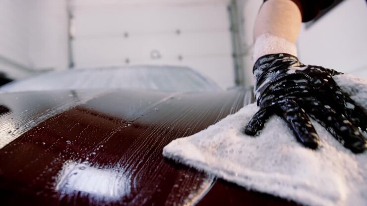 Scrubbing soap across red car hood