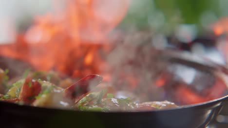 verduras flambé lanzadas en una sartén con llamas altas