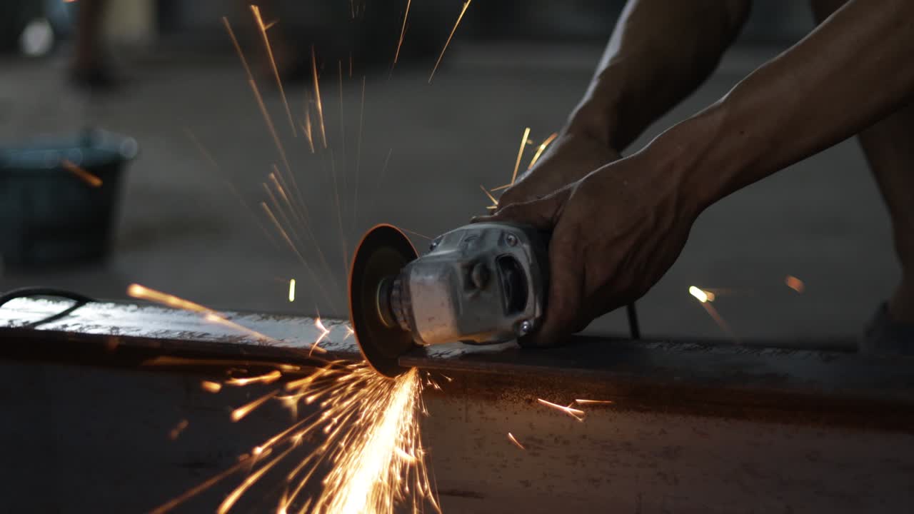 un trabajador de la construcción está cortando metal con una molienda sin usar guantes y equipos de seguridad