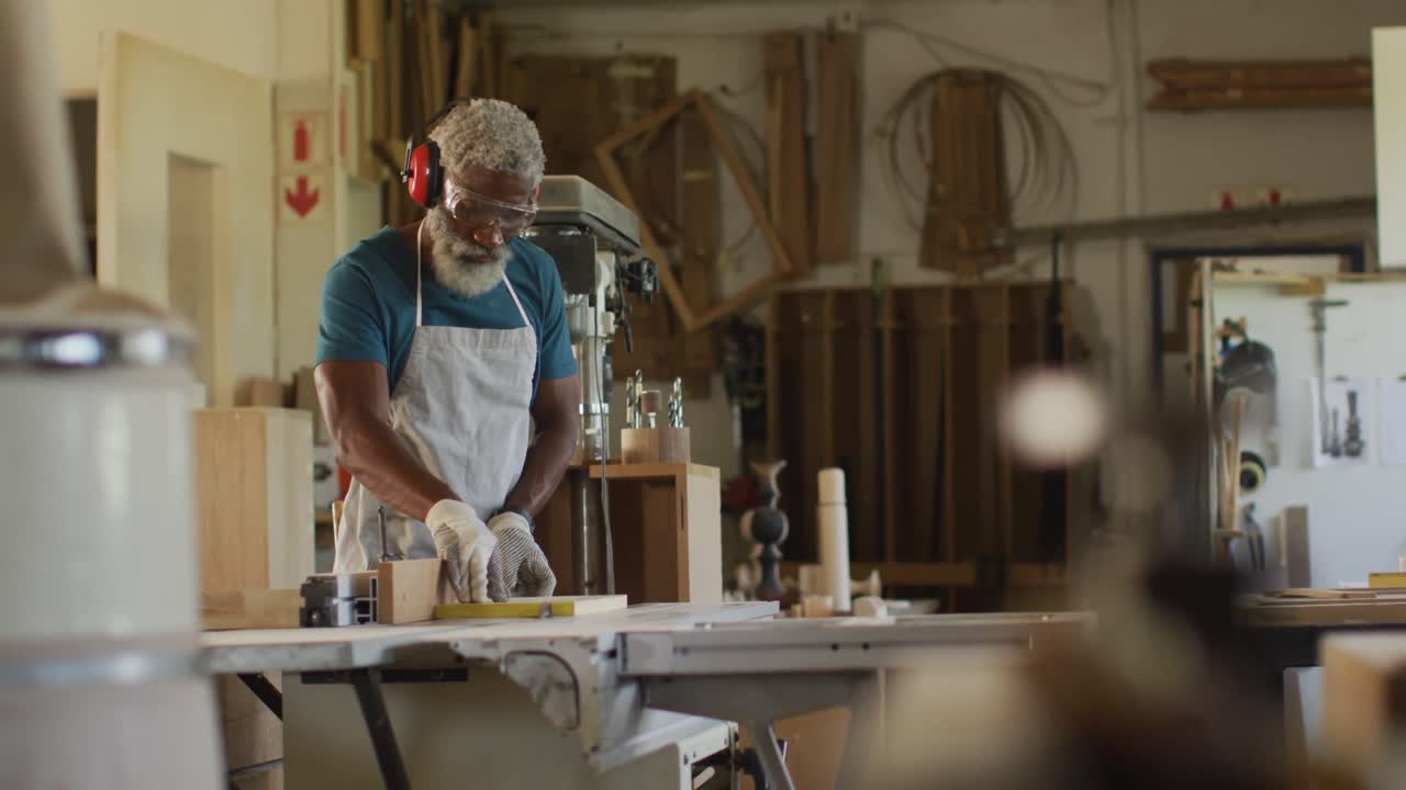 African american male carpenter using table saw for cutting wood at a carpentry shop