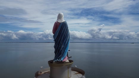 aerial flies past sculpture of mary on shore of parana river in brazil