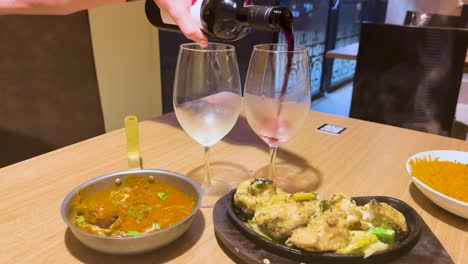 wine poured alongside steaming indian curry dishes