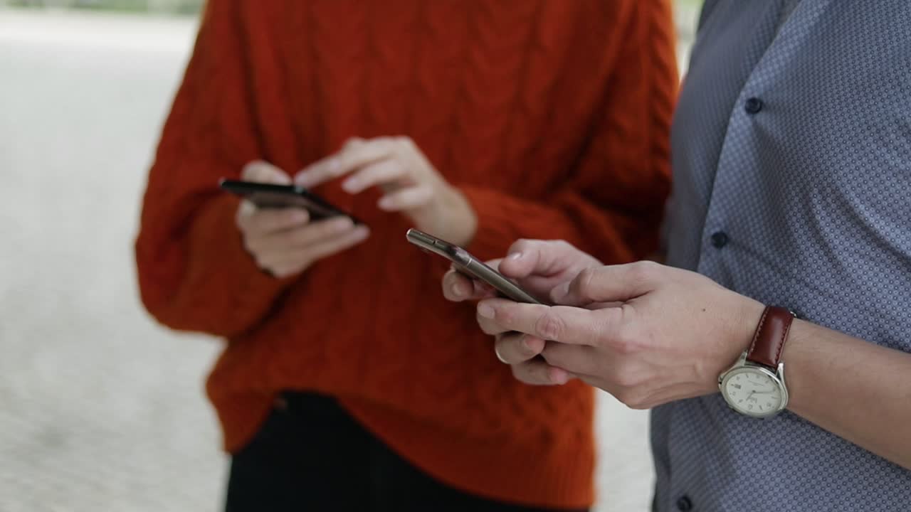 hombre y mujer usando teléfonos celulares al aire libre