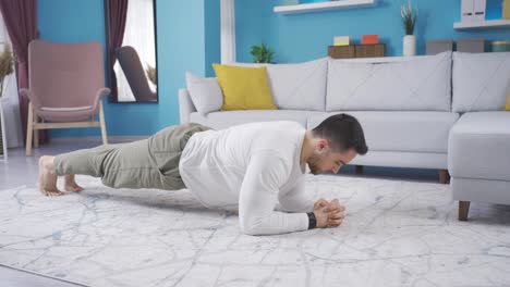 un joven culturista haciendo tablas en casa solo.